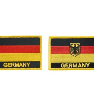 May include: Two embroidered iron-on patches featuring the German flag. The patches are yellow with black and red stripes. One patch has the German eagle emblem. Both patches have the word "GERMANY" written below the flag.