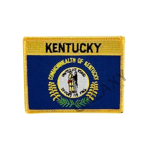 May include: Embroidered patch of the Kentucky state flag. The flag is blue with a gold border and features the state seal in the center. The seal depicts two figures shaking hands, with the words "Commonwealth of Kentucky" and "United We Stand, Divided We Fall" surrounding them.