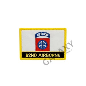 May include: A yellow and black embroidered patch with a white background. The patch features the 82nd Airborne Division insignia, a red circle with a blue parachute inside, and the text "AIRBORNE" above the circle and "82ND AIRBORNE" below the circle.