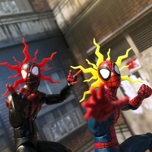May include: Two action figures of Spider-Man with different colored hair. One figure has red hair and is wearing a black and red suit. The other figure has yellow hair and is wearing a red and blue suit.