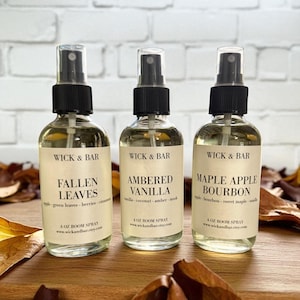 May include: Three glass spray bottles of room spray with black caps and labels. The labels read "Fallen Leaves", "Ambered Vanilla", and "Maple Apple Bourbon". The bottles are 4 oz each and are from Wick & Bar.