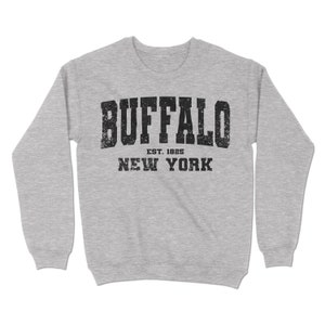 May include: A grey sweatshirt with the text "BUFFALO EST. 1825 NEW YORK" printed in black.