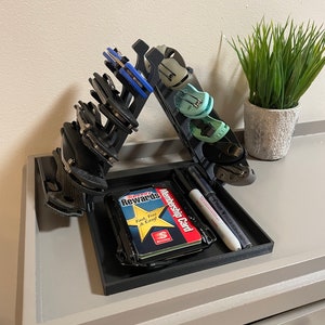 May include: A black 3D printed organizer with a tray for holding cards, pens, and other small items. The organizer has a vertical section for holding multiple pocket knives. The tray contains a Speedy Rewards card, a membership card, and a black marker pen.