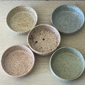 May include: Five small ceramic bowls with speckled glaze in various shades of blue, brown, and white.