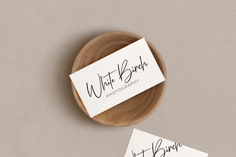 K&ouml;nnte beinhalten: Wei&szlig;e Visitenkarte mit dem Text "White Birch Photography" in handschriftlicher Schrift auf einer Holzoberfl&auml;che.