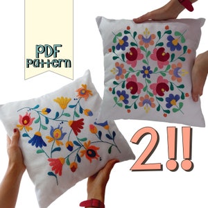 May include: Two white throw pillows with colorful floral embroidery. One pillow features a symmetrical design, while the other has a flowing floral pattern. The pillows are held up by hands. The image also includes the text "PDF pattern" and the number "2!!".