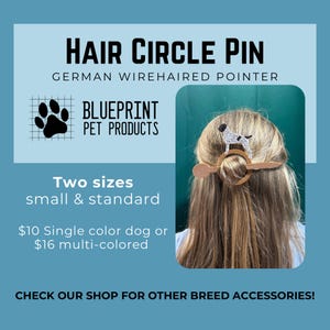 May include: A hair circle pin featuring a German Wirehaired Pointer dog silhouette. The accessory consists of a circular wooden ring and a flat wooden stick used to secure hair. The text HAIR CIRCLE PIN, GERMAN WIREHAIRED POINTER, and BLUEPRINT PET PRODUCTS is visible.