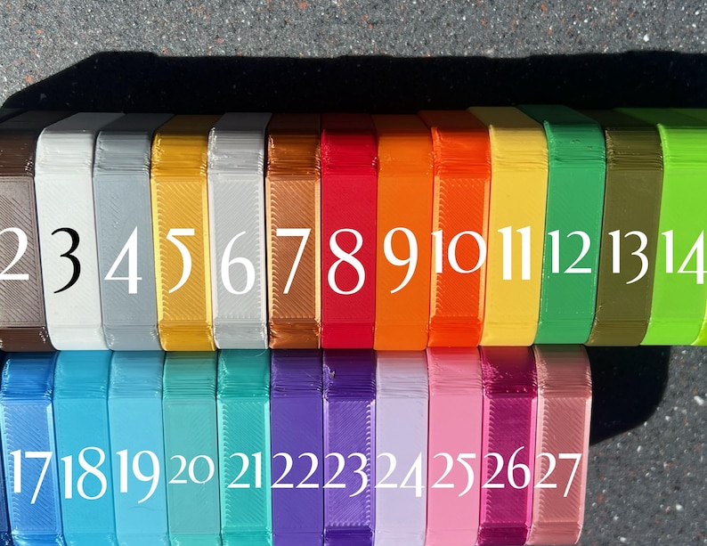 May include: A row of 27 small, rectangular boxes, each a different color. The boxes are numbered 1 through 27. The boxes are arranged in two rows, with the first row containing boxes 1 through 14 and the second row containing boxes 15 through 27.