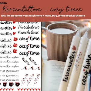 Könnte beinhalten: Drei weiße Kerzen mit schwarzem Text und Illustrationen. Die Kerzen sind mit "Kerzenwetter", "cozy time" und "cozy time" beschriftet. Die Kerzen stehen auf einem Buch und einer braunen Oberfläche.