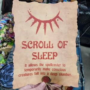 May include: A parchment-style scroll with the words "SCROLL OF SLEEP" in red. The scroll has a red eye-like symbol at the top and a wax seal at the bottom. The text below reads, "It allows the spellcaster to temporarily make conscious creatures fall into a deep slumber."