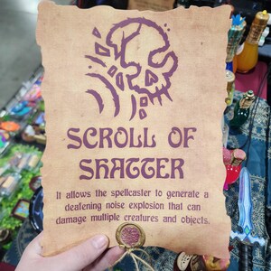 May include: A parchment scroll with the text "SCROLL OF SHATTER" and a skull illustration in purple. The scroll's description states it allows the spellcaster to generate a deafening noise explosion. A wax seal is at the bottom.