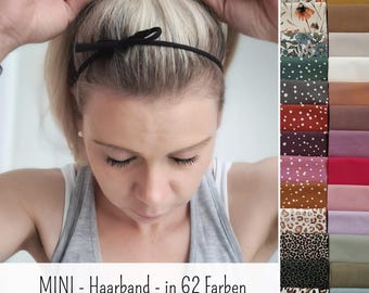 May include: A thin black headband with a small bow detail. The image displays a variety of fabric swatches in 62 different colors and patterns, including solid tones, polka dots, leopard prints, and floral designs, with the text MINI - Haarband - in 62 Farben.