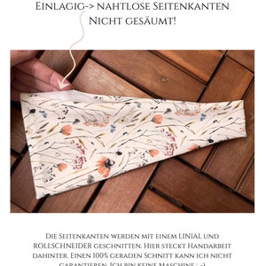May include: A single-layer headband with a cream background featuring a botanical print of orange, blue, and brown wildflowers. The text reads: WICHTIGER HINWEIS, EINLAGIG-> NAHTLOSE SEITENKANTEN NICHT GES&Auml;UMT!, DIE SEITENKANTEN WERDEN MIT EINEM LINIAL UND ROLLSCHNEIDER GESCHNITTEN. HIER STECKT HANDARBEIT DAHINTER. EINEN 100% GERADEN SCHNITT KANN ICH NICHT GARANTIEREN. ICH BIN KEINE MASCHINE ; -) DIE SEITENKANTEN ROLLEN SICH NACH DEM ERSTEN MAL TRAGEN &bdquo;GEWOLLT&ldquo; NACH INNEN. SIE UMS&Auml;UMEN SICH SOZUSAGEN SELBST :-)