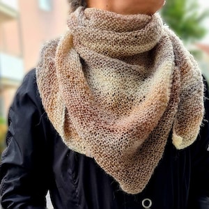 May include: A brown and beige knitted scarf with a gradient pattern. The scarf is draped around a person's neck.