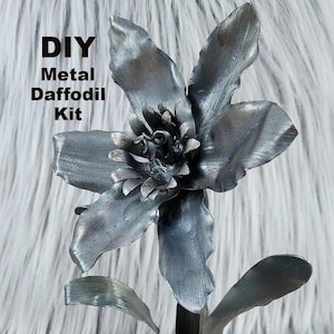 May include: DIY Metal Daffodil Kit. A metal daffodil sculpture with a hexagonal base. The flower is made of metal and has a silver finish.