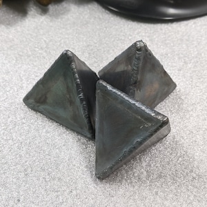 May include: Three gray metal triangular shapes, possibly used for grinding or polishing.