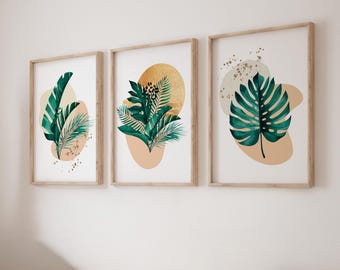 May include: A set of three framed wall art prints featuring green tropical leaves, including monstera and palm fronds, layered over beige abstract shapes and a gold circular accent with leopard print details and gold paint splatters.