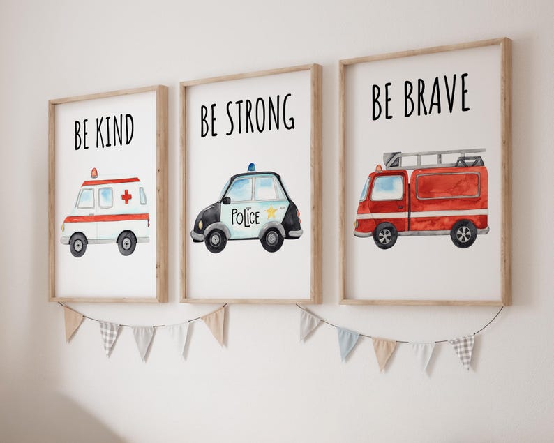 May include: Three framed wall art prints featuring watercolor illustrations of emergency vehicles. The first shows an ambulance with the text BE KIND, the second a police car with BE STRONG, and the third a fire truck with the text BE BRAVE.