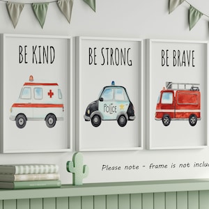May include: Three framed wall art prints featuring watercolor illustrations of emergency vehicles. The first shows an ambulance with the text BE KIND, the second a police car with BE STRONG, and the third a fire truck with the text BE BRAVE.