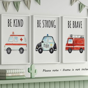 May include: Three framed wall art prints featuring watercolor illustrations of emergency vehicles. The first shows an ambulance with the text BE KIND, the second a police car with BE STRONG, and the third a fire truck with the text BE BRAVE.