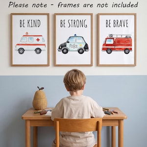 May include: Three wall art prints featuring watercolor illustrations of emergency vehicles. The first shows an ambulance with the text BE KIND, the second a police car with BE STRONG, and the third a fire truck with BE BRAVE. Please note - frames are not included.