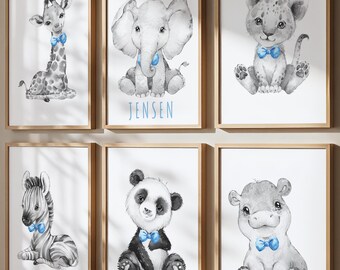 May include: Six framed wall art prints featuring watercolor illustrations of a baby giraffe, elephant, lion, zebra, panda, and hippo. Each animal is rendered in shades of gray and wears a bright blue bow tie. The elephant print includes the name JENSEN.