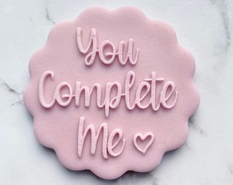 May include: Pink fondant cookie with the text "You Complete Me" and a small heart.