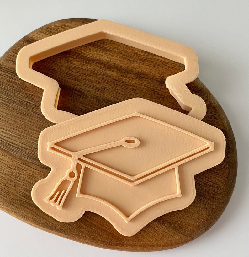 Plastic graduation diploma cookie embosser stamp tool on marble surface