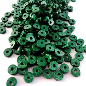 Puede incluir: Un montón grande de cuentas de madera verdes en forma de anillo. Las cuentas son todas del mismo tamaño y tienen un acabado liso.