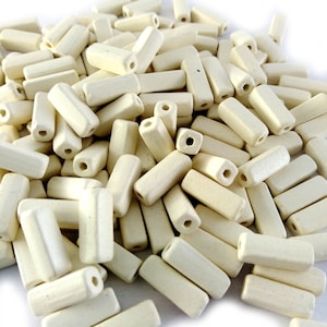 Peut inclure: Un tas de perles rectangulaires en céramique blanc cassé avec un trou au centre de chaque perle.