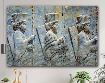 May include: A close-up of a stone relief carving depicting three figures in profile, each holding a spear and shield. The figures are carved in a bas-relief style, with their bodies and clothing rendered in detail. The stone is a light gray color, with some areas of darker gray and brown.