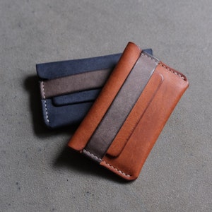 May include: Two leather wallets, one brown and one blue, with a gray leather accent. Both wallets have a stitched edge.