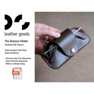 以下が含まれることがあります： スナップ留めの茶色の革製メガネケースで、メガネが1組入っています。「leather goods」と「The Glasses Holder Printable PDF Pattern」の文字が見えます。