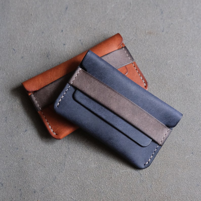 May include: Two leather wallets, one brown and one blue, with a brown leather strap on the blue wallet.