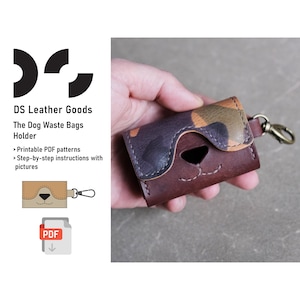 May include: A brown leather dog waste bag holder with a camouflage pattern on the top flap. The holder has a small dog face cutout and a metal ring for attaching to a leash. The holder is being held in a hand.