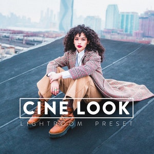 Puede incluir: Una mujer con un abrigo de cuadros rojos y negros y pantalones marrones se sienta en una azotea con una vista de la ciudad al fondo. El texto "CINE LOOK LIGHTROOM PRESET" se muestra en la imagen.