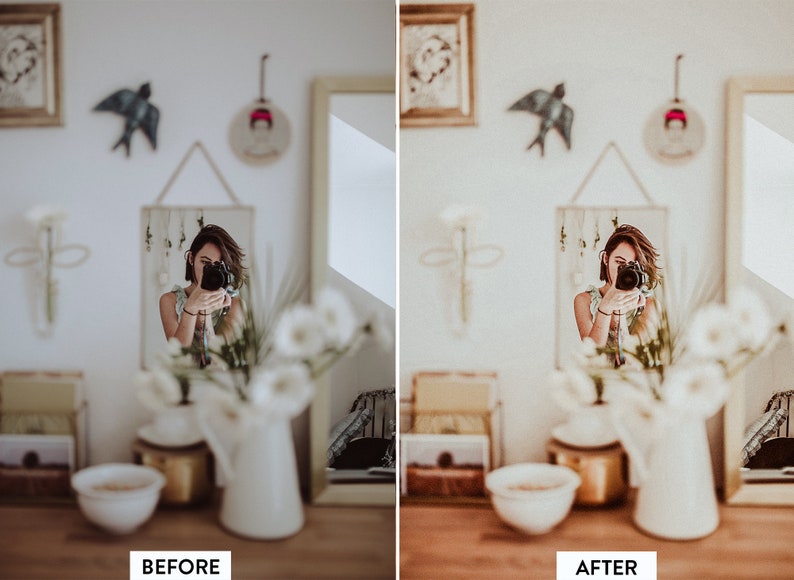 May include: A woman takes a selfie in a mirror, with white flowers in a vase in the foreground. The room is decorated in a bohemian style with framed artwork and a bird figurine on the wall.