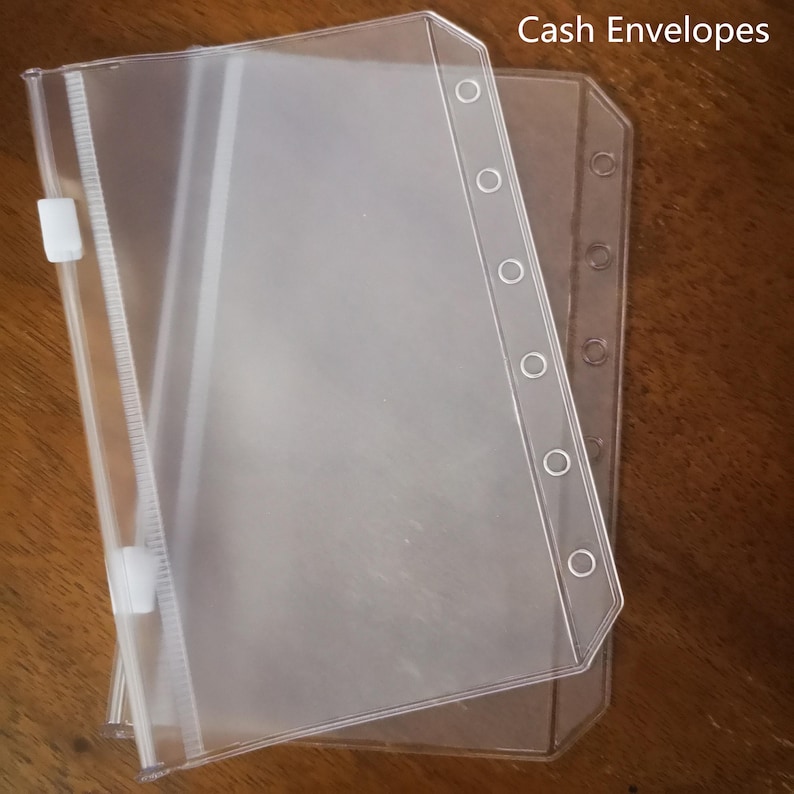 May include: Two clear plastic cash envelopes with a zipper closure and holes for a binder. The envelopes are labeled "Cash Envelopes".