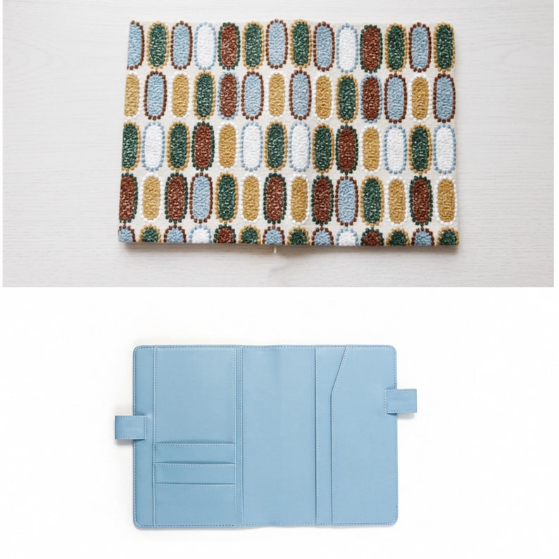 Pode incluir: Um conjunto de duas pe&ccedil;as com uma capa de caderno e uma capa de caderno a condizer. A capa superior tem um fundo creme com um padr&atilde;o repetitivo de ovais coloridos. A capa inferior &eacute; azul claro com bolsos interiores.