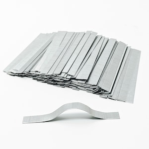 May include: A large stack of silver metal strips, with one strip bent into an arch shape. The strips are approximately 1 inch wide and 3 inches long.