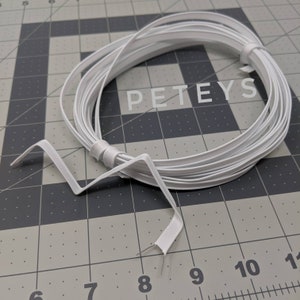 May include: A white plastic wire, coiled and ready to be used. The wire is about 1/4 inch wide and is flexible. The wire is labeled "PETEYS".