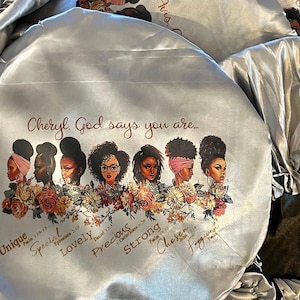 May include: A silver satin sleep cap with a printed design of women with flowers and the text "Cheryl. God says you are... Unique, Special, Lovely, Precious, Strong, Chosen".