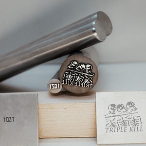 Può includere: Tre timbri metallici con le parole "Triple Kill" e "10ZT" incise. I timbri sono argentati e hanno un design a forma di teschio.