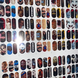 May include: A sheet of nail art transfers showcasing horror film characters and scenes. Designs include images from "The Shining," "Scream," "Child's Play," and "Friday the 13th." The transfers are oval-shaped and printed on a white background.