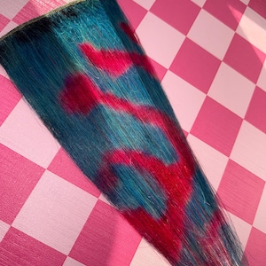 May include: A vibrant blue and red hair extension. The hair is a deep blue with streaks of bright red, creating a bold and colorful contrast. The extension is likely for adding length or highlights to existing hair.