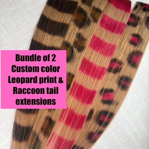 Può includere: Quattro extension per capelli con motivi e colori distinti. Una presenta strisce da coda di procione marroni e bionde, un'altra macchie di leopardo marroni, una strisce rosa brillante e l'ultima macchie di leopardo rosa e nere. Testo: Bundle of 2 Custom color Leopard print & Raccoon tail extensions.