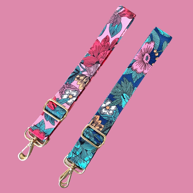 Pode incluir: Duas correias ajust&aacute;veis com padr&otilde;es florais. Uma correia &eacute; rosa com flores vermelhas, brancas e verdes. A outra correia &eacute; azul com flores rosa, verdes e brancas.