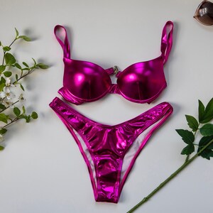 May include: A pink metallic bikini set with a halter top and high-cut bottoms.