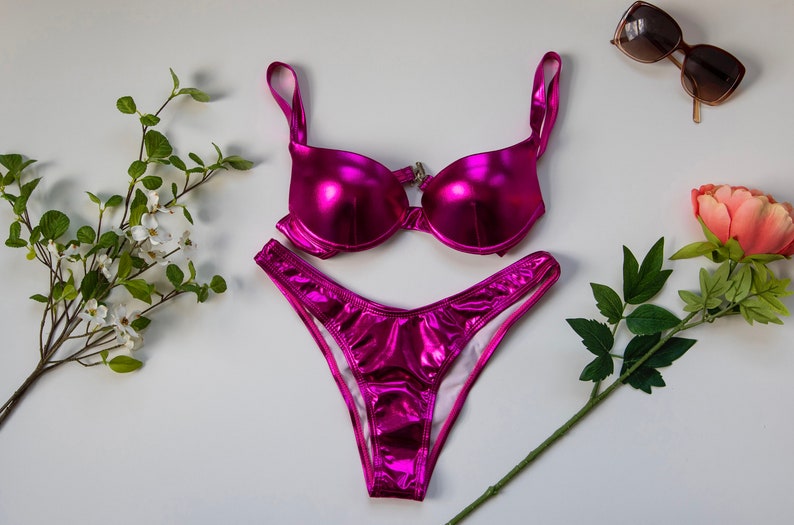 May include: A pink metallic bikini set with a halter top and high-cut bottoms.