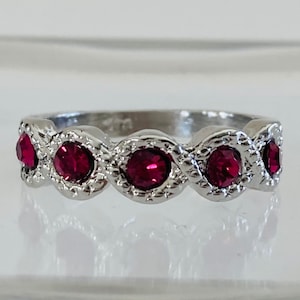 May include: A silver ring with a wavy band and five red gemstones.
